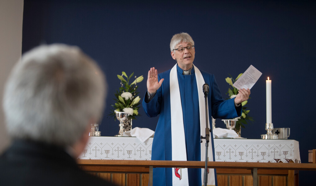 Biskoppen i Metodistkirken står foran alteret og taler.